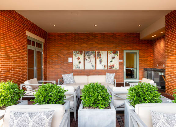 a patio with white couches and chairs and a fireplace
