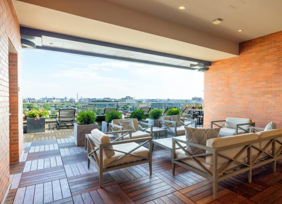 a terrace with chairs and tables and a brick wall with a view of the city
