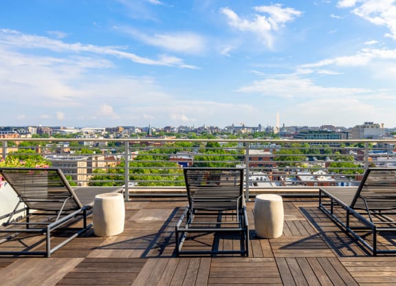 a rooftop deck with chairs and a view of the city
