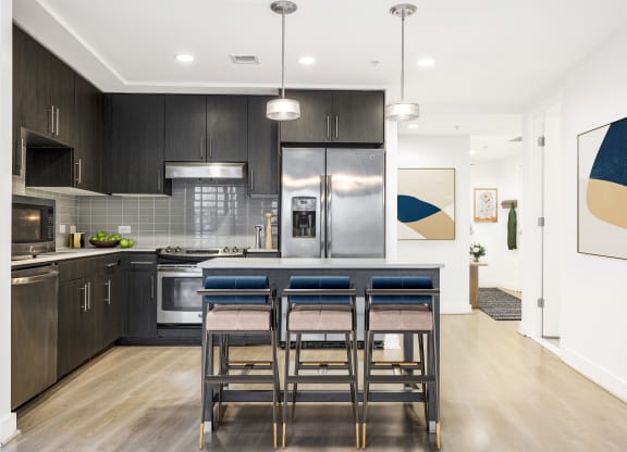 a kitchen with dark cabinets and a large island with a breakfast bar
