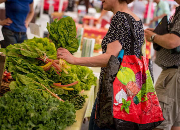 A woman is shopping for vegetables at a market.