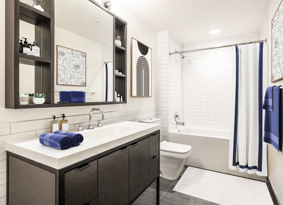 a bathroom with white tile walls and a white sink with a blue towel on it