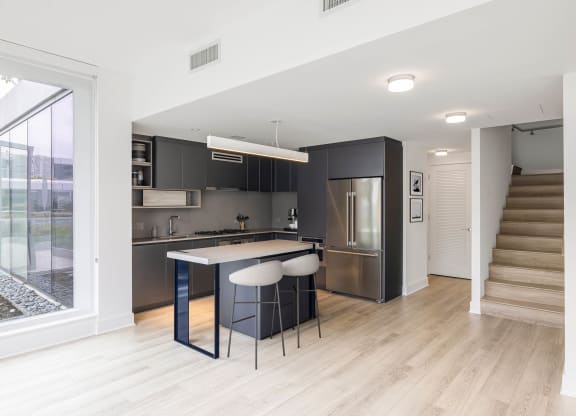 a kitchen with black cabinetry and a white counter top with three stools