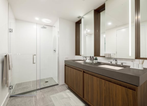 a bathroom with a large vanity with two sinks and a walk in shower