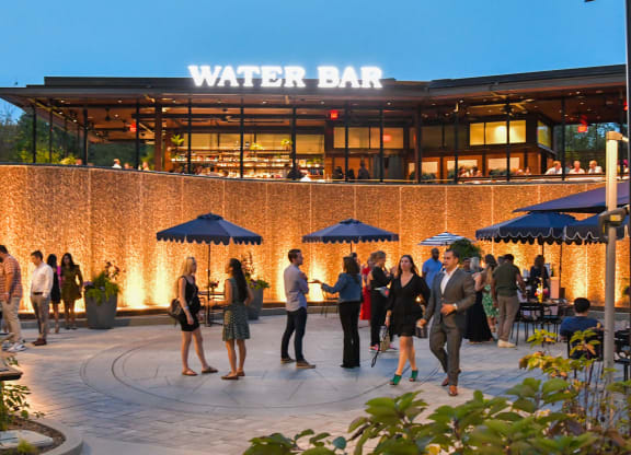 people standing outside of a water bar at night