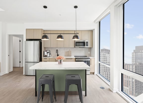a kitchen with an island and two stools in front of a window