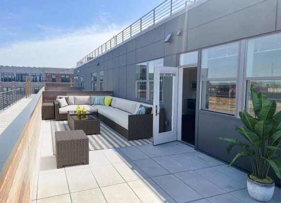 a rooftop terrace with couches and tables on a building