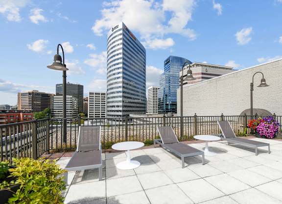 A rooftop patio with a table and chairs overlooking a city skyline.