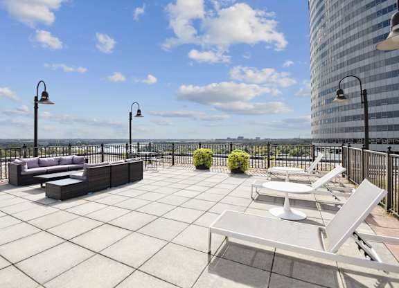 A patio with a couch, chairs, and a table with a view of the water.