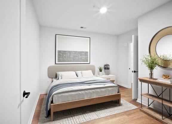 a bedroom with white walls and a bed with a gray blanket