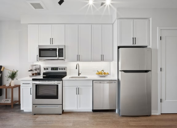 a white kitchen with stainless steel appliances and white cabinets
