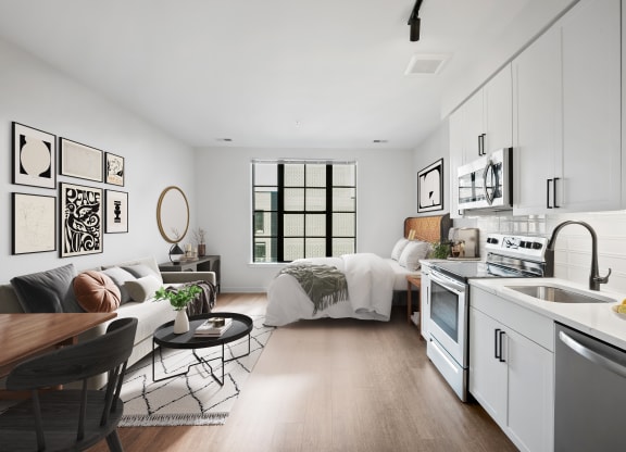 a white living room with a kitchen and a bed