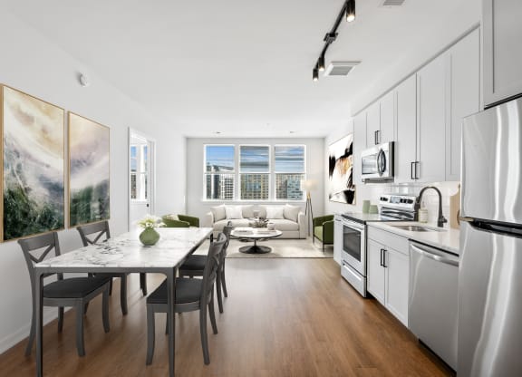 a kitchen and living room with white cabinets and a table and chairs