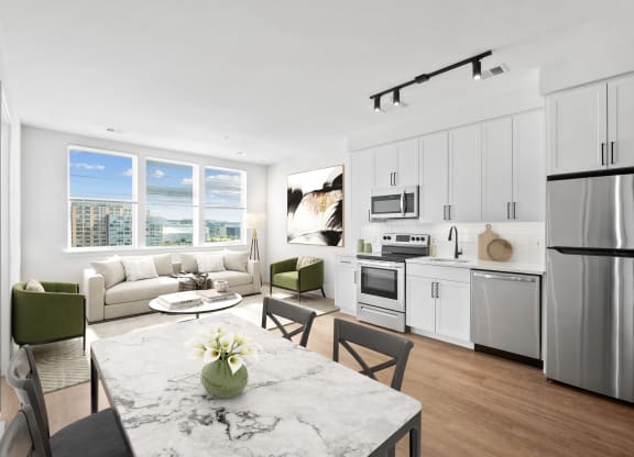 a kitchen and living room with white cabinets and stainless steel appliances