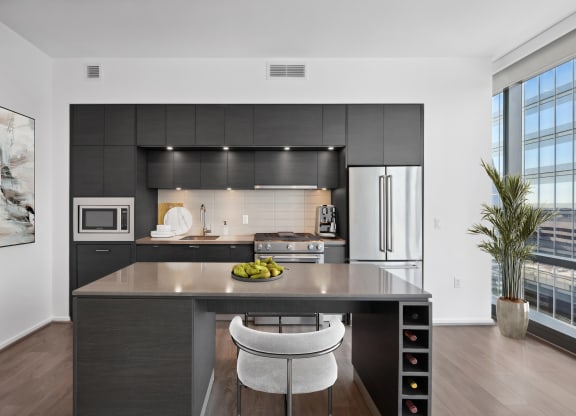a kitchen with black cabinetry and a island with a bowl of fruit