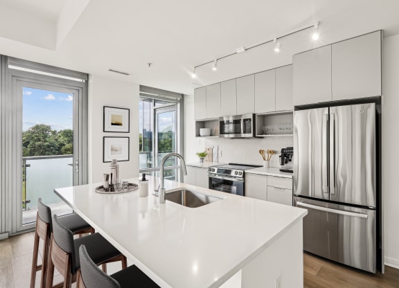 a white kitchen with a large island and stainless steel appliances