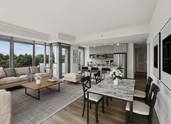 a living room with couches and a table and a kitchen with a large window