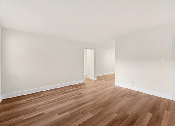 A room with wooden flooring and white walls.