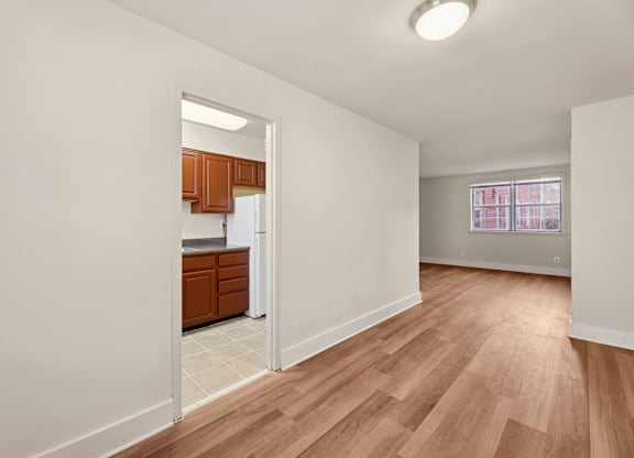 A kitchen with wooden cabinets and a refrigerator is visible through an open door.