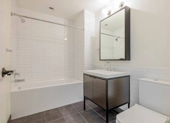 A white bathroom with a black cabinet and a white toilet.