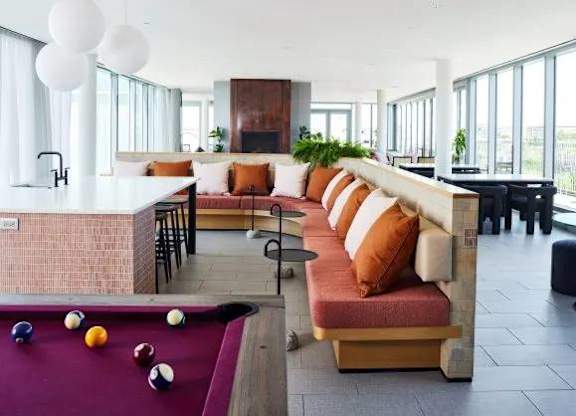 A billiard table is in the middle of a room with a long couch.