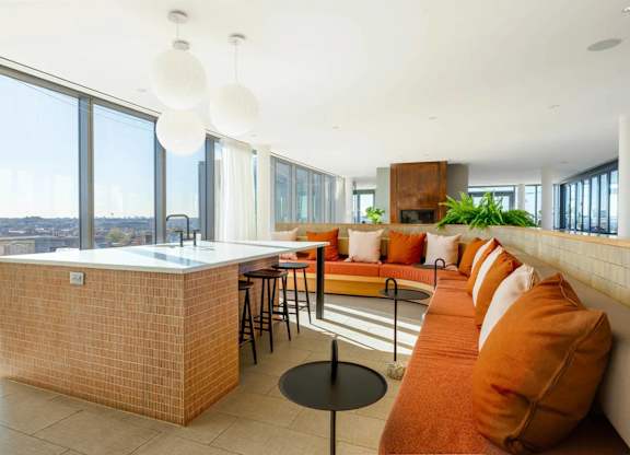 A kitchen with a brick counter and a long orange couch.