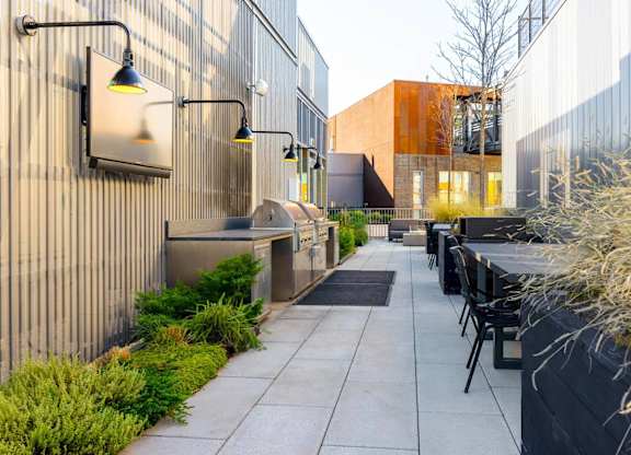 A patio with chairs and a table is surrounded by a wall with a flat screen TV mounted on it.