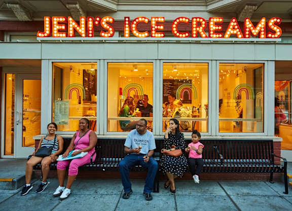 A family of four sits on a bench outside Jenni's Ice Creams.