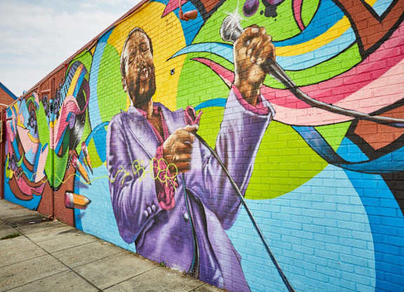 A mural of a man in a purple suit holding a microphone.