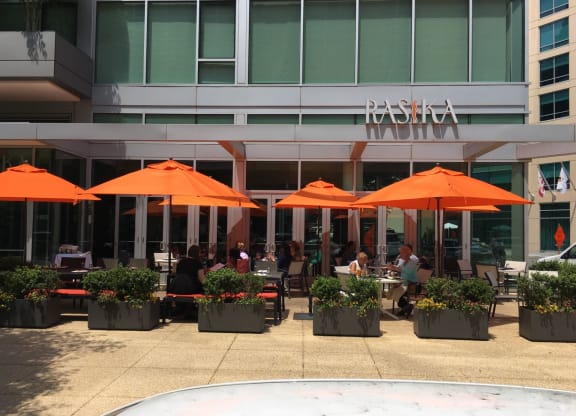 an outdoor restaurant with orange umbrellas in front of a building