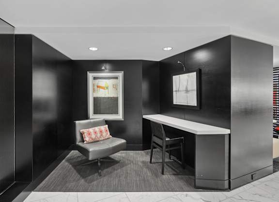 A black and white photo of a room with a couch, chair, and desk.