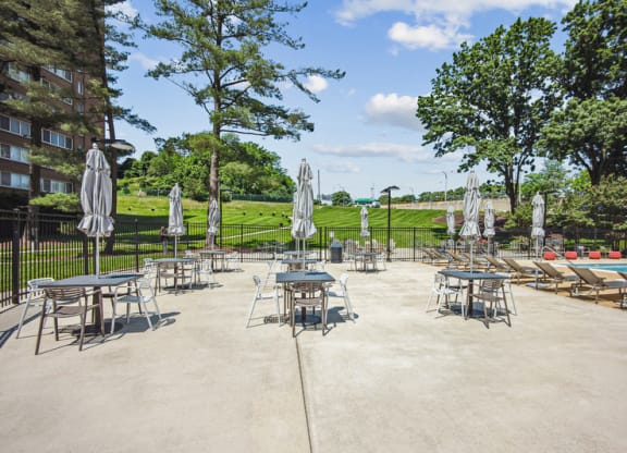 a patio with tables and umbrellas next to a pool