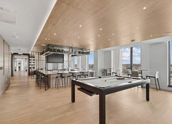 A billiard table is in the middle of a room with a bar and a kitchen in the background.