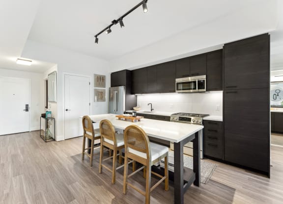 a kitchen with a white island and wooden chairs at The Grace and Reva, Virginia, 22202