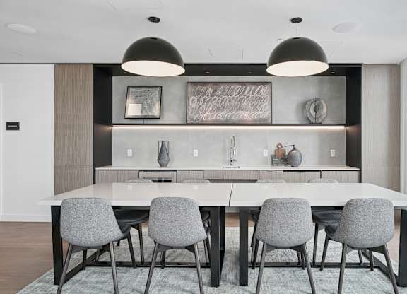 A modern dining room with a large table and grey chairs.