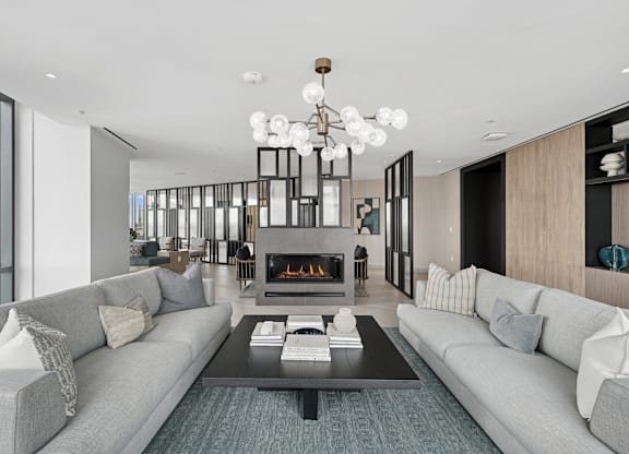 A modern living room with a grey couch, a coffee table, and a fireplace.