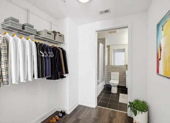 a closet with clothes and a bathroom with a toilet