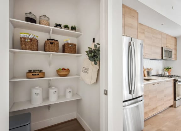 a kitchen with white shelves and a stainless steel refrigerator at The Grace and Reva, Virginia, 22202
