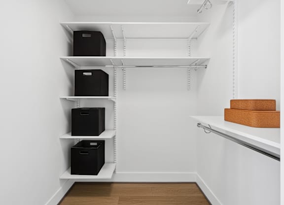 A white shelving unit with black boxes and brown boxes on top.