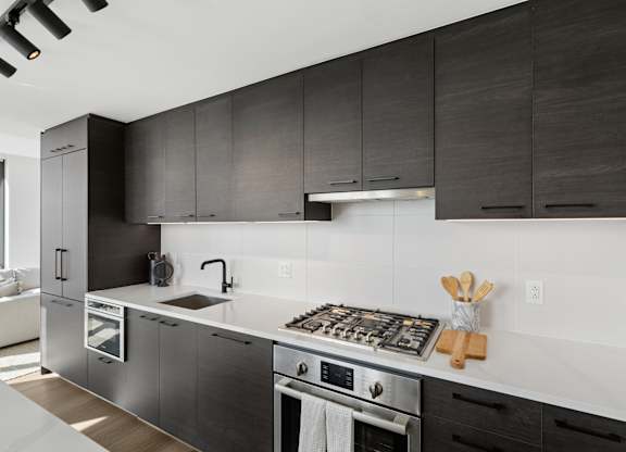 A modern kitchen with dark wood cabinets and stainless steel appliances.