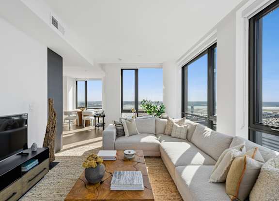 A modern living room with a large white sofa and a flat screen TV.