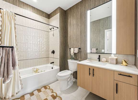 A modern bathroom with a white tub, sink, and toilet.