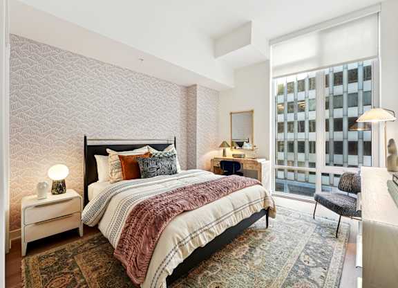 A bedroom with a large bed and a window overlooking a building.