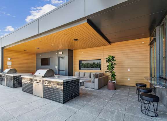 A modern outdoor seating area with a wooden exterior and a glass wall.
