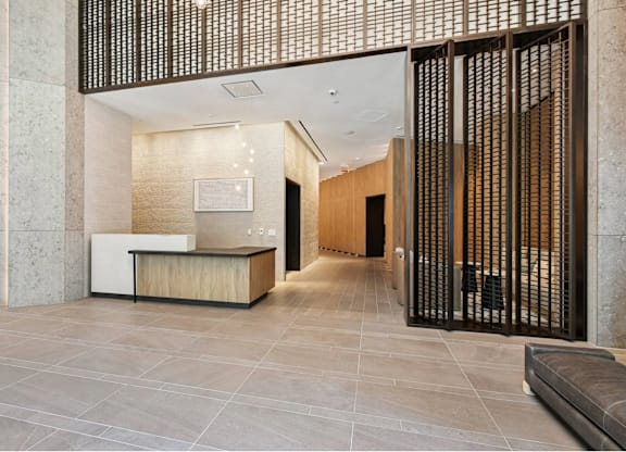 A modern office lobby with a reception desk and a large screen on the wall.