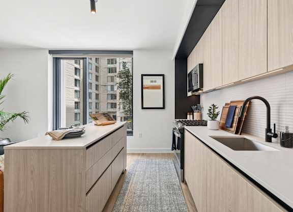 A modern kitchen with wooden cabinets and a large window.