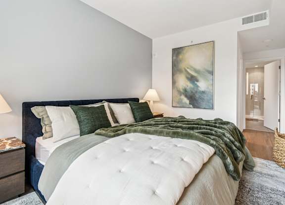 A bedroom with a large bed and a painting on the wall.