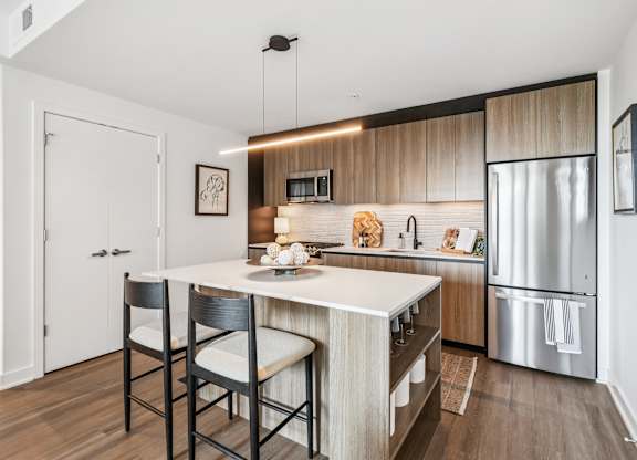 A modern kitchen with a white island and wooden cabinets.