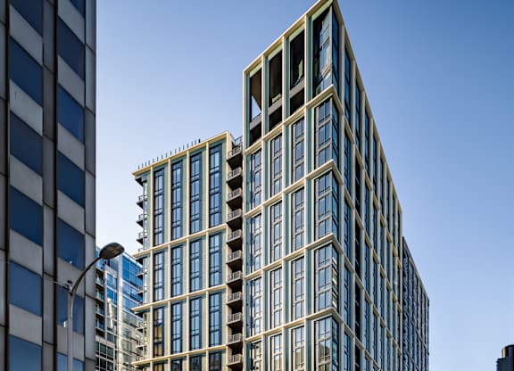 A tall building with many windows is located on a street corner.