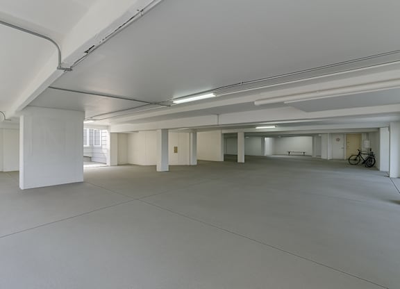 A large, empty, white room with a bicycle in the background.